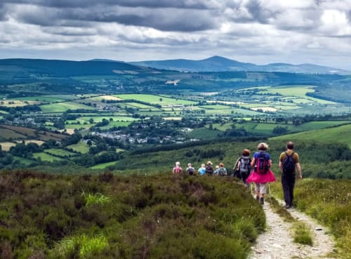 Group of hikers on a trail overlooking the lush green valleys and mountains of Wicklow, Ireland