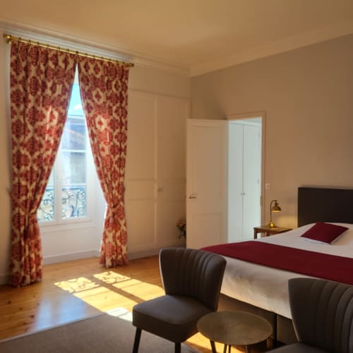 Chambre lumineuse Chesnel aux Logis des Tourelles, Cognac, avec rideaux en damas rouge, parquet et vue sur la ville