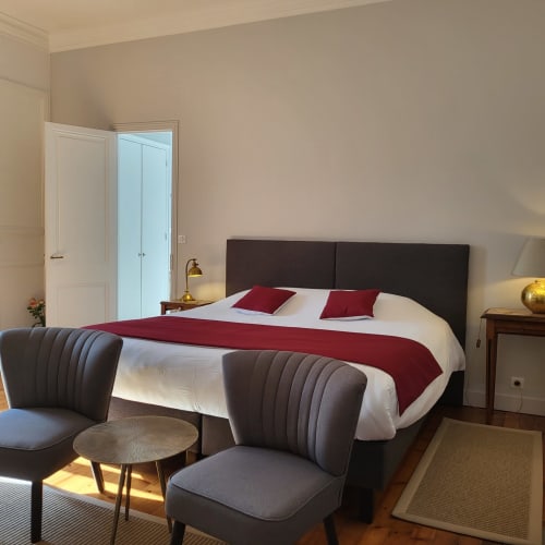 Chambre élégante au Logis des Tourelles, Cognac avec tête de lit sombre, accents bourgognes et vue sur la ville
