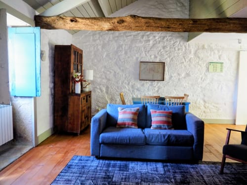 Aconchegante sala de estar com sofá azul, vigas de madeira, paredes brancas e soalho de madeira na Quinta da Coutada em Portugal