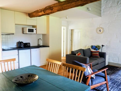Cozinha, sala de refeições e sala de estar integradas num apartamento T2 em Quinta da Coutada, Portugal, com teto de vigas de madeira