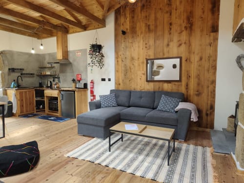 Casa Azorina villa living room with gray sofa, wooden beams, kitchen, and mountain views in Fajazinha