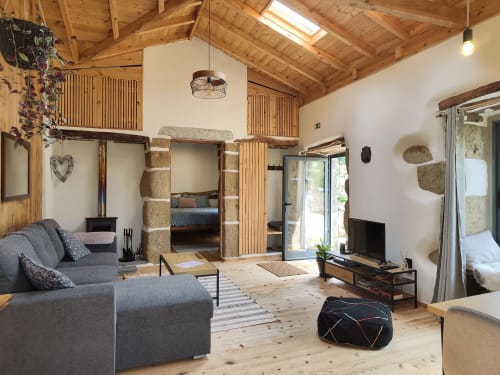 Casa Azorina villa living room with exposed wood beams, stone bedroom alcove, gray sofa, fireplace, and mountain views in