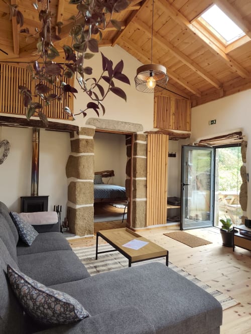Casa Azorina villa living room with stone fireplace, wooden beams, gray seating, and mountain views at Casas Florescer