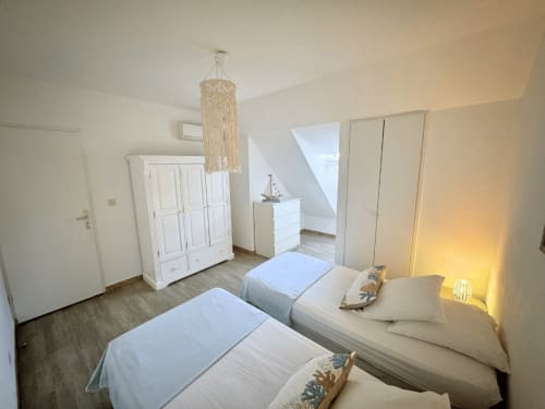 Twin bedroom at Horizon Doré hotel in Gourbeyre with white wardrobe, macramé pendant lamp, and coastal decor