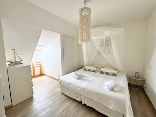Bright attic bedroom at Horizon Doré in Gourbeyre with canopy bed, macramé chandelier, and skylight