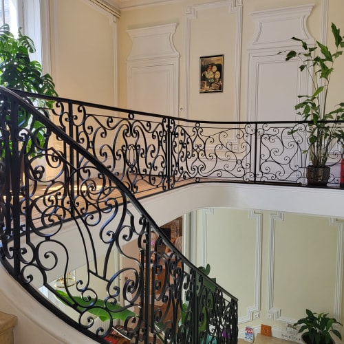 Élégant escalier aux rampes en fer forgé ouvragé au Logis des Tourelles, charmant gîte à Cognac, France