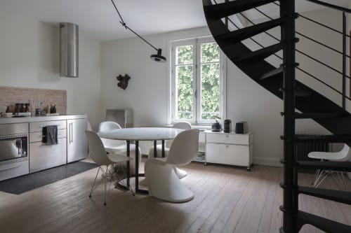 Modern studio with dining table, white chairs, kitchen, spiral staircase, and garden views at Villa Sonneville in Roubaix