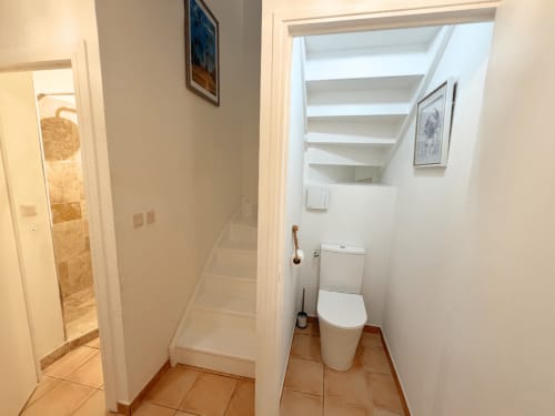 Modern bathroom corridor at Horizon Doré hotel in Gourbeyre with white toilet, tiled flooring, and shower entrance.
