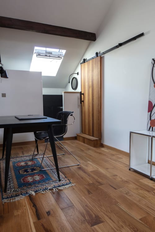 Modern attic bedroom at Villa Sonneville with desk, wooden sliding door, skylight, and parquet flooring in Roubaix