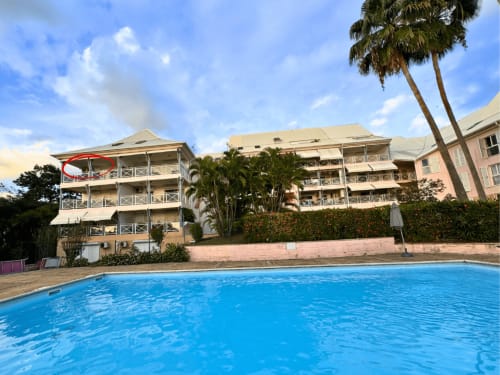 Horizon Doré hotel pool with beachfront building, palm trees, and blue sky in Gourbeyre, Guadeloupe