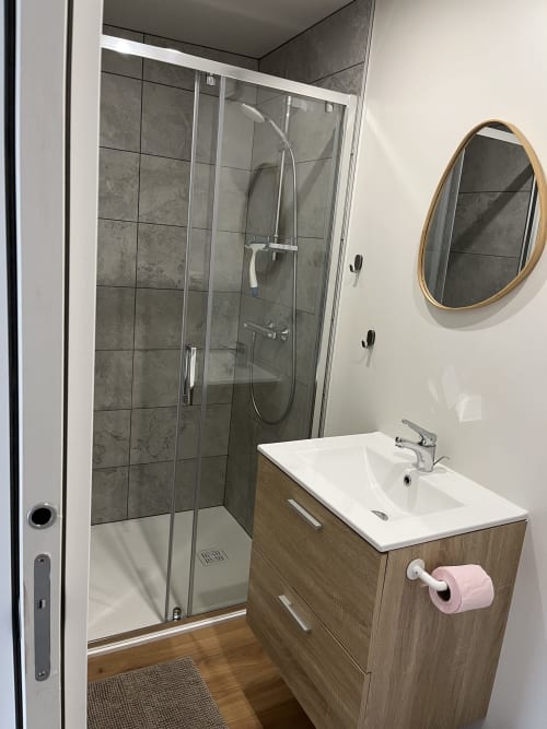 Salle de bain moderne du Studio Le Gacet aux Logis du canal, Betton, avec douche, vasque et miroir rond