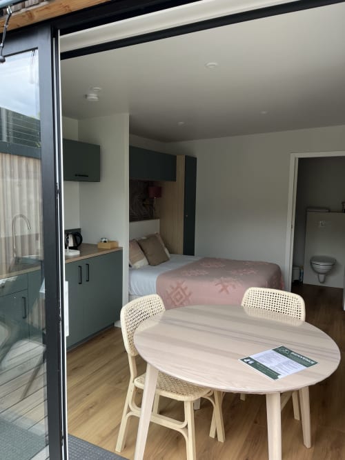 Studio moderne aux Logis du canal à Betton avec table à manger, kitchenette et chambre avec TV visible