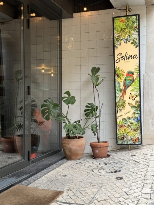 Entrada da Selina Lisboa com plantas em vasos e parede de azulejos do banheiro ao fundo em Ribeirinha, Portugal