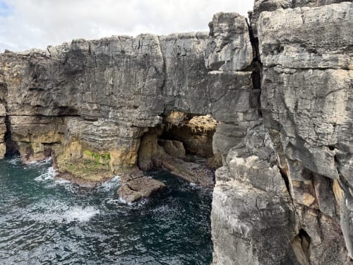 Falésias rochosas costeiras com gruta marinha natural em Ribeirinha, Portugal perto da Villa Golden Mermaid