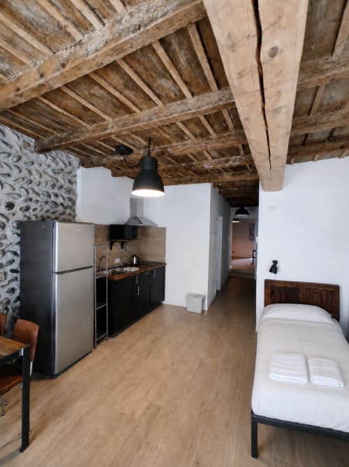 Modernes Studio-Apartment in Bergamo mit freiliegenden Holzbalken, Küchenzeile, Bett und rustikaler Steinwand