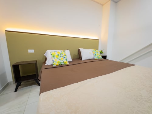 Habitación moderna del hotel La Puerta del Angel en Ricaurte con cama matrimonial, cabecera amarilla y cojines decorativos floral