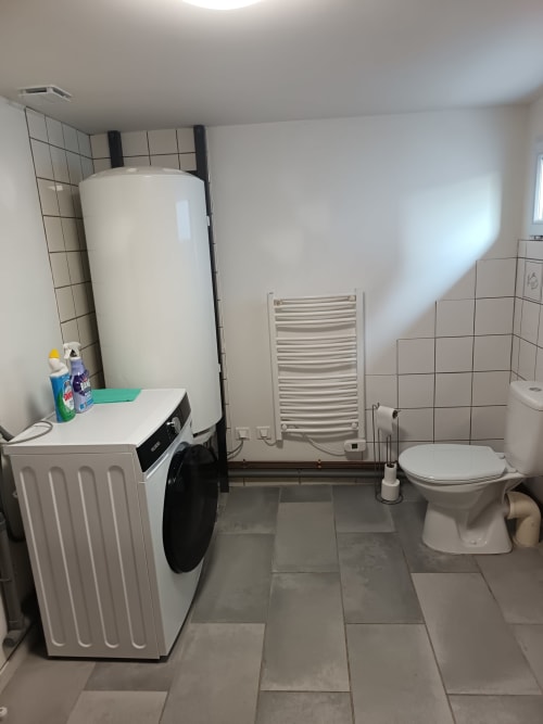 Bathroom at Maison Le Wetz with washing machine, water heater, heated towel rack, and toilet