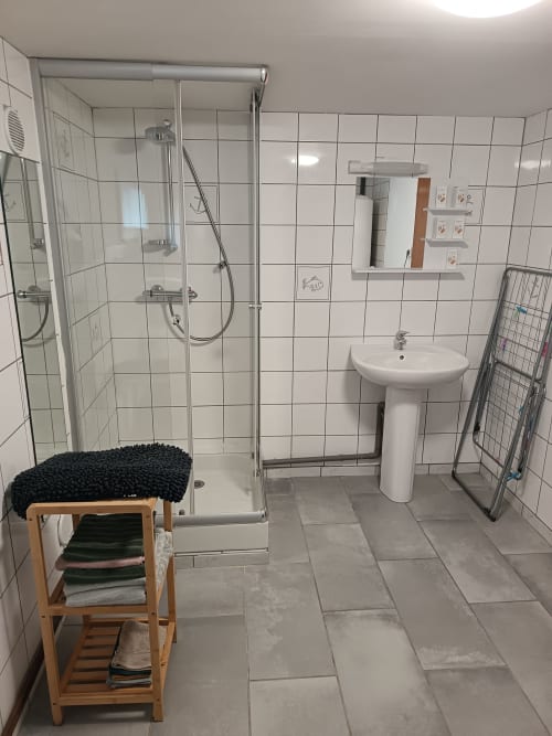 Modern shared bathroom with walk-in shower, pedestal sink, and heated towel rail at Les Meublés d'Hélène apartment in France