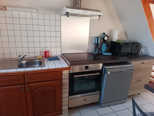 Kitchen in Les Meublés d'Hélène apartment with oven, dishwasher, sink, and basic cooking equipment
