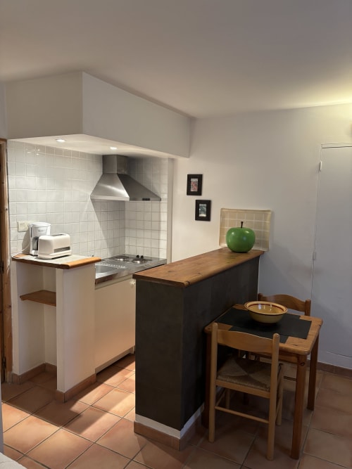 Kitchenette moderne avec crédence en carrelage blanc, comptoir en bois, coin repas avec pomme verte, suite Eglantine à Anne De La