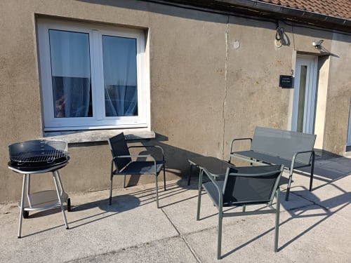 Outdoor patio area at Les Meublés d'Hélène with BBQ grill, lounge chairs, and table seating