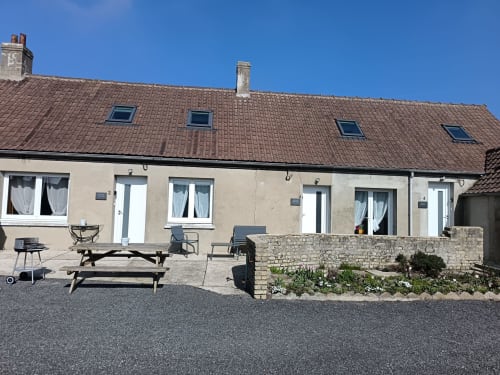 Les Meublés d'Hélène apartment exterior with terrace, picnic tables, and stone wall in Sainte-Marie-Kerque