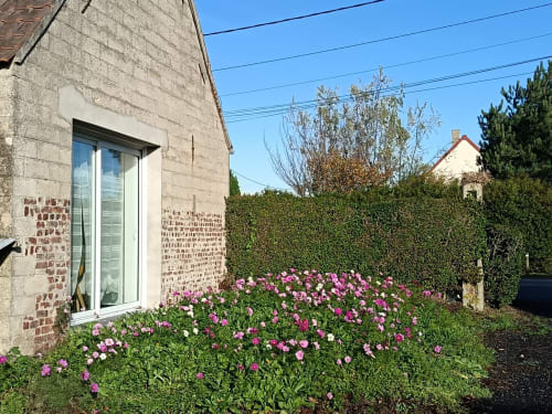 Cottage en brique avec fleurs roses, haie verte et fenêtre de l'appartement Les Escardines à Sainte-Marie-Kerque