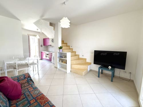 Moderna zona living dell'Appartamento Puglia Estate con cucina, scale in legno, TV e arredi colorati