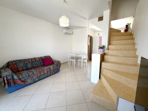 Villetta Puglia Estate, soggiorno con divano colorato, tavolo da pranzo, scale e lampadari a sospensione