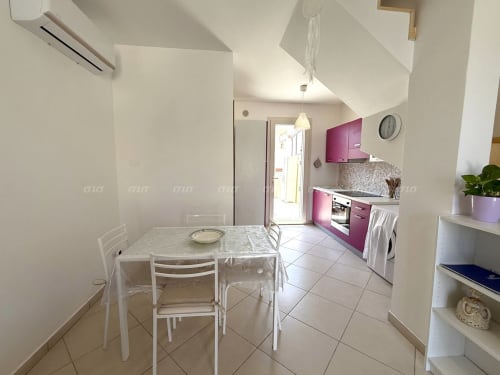 Cucina e zona pranzo moderna dell'appartamento Villetta Alba a Puglia Estate, con mobili viola e tavolo bianco