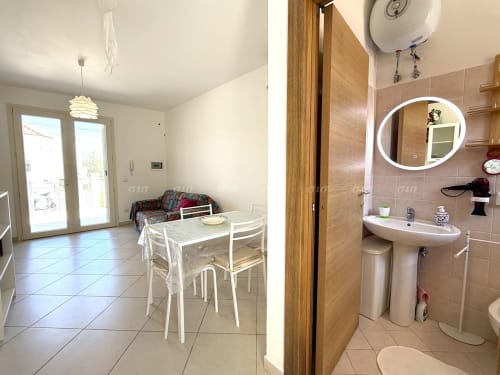 Appartamento Villetta Alba a Puglia Estate: luminosa zona cucina-soggiorno con tavolo da pranzo e bagno moderno con lavabo su colonna