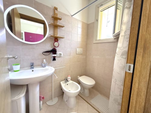 Bagno moderno della Villetta Alba presso Puglia Estate, con lavabo in ceramica bianca, bidet, toilette e specchio rotondo