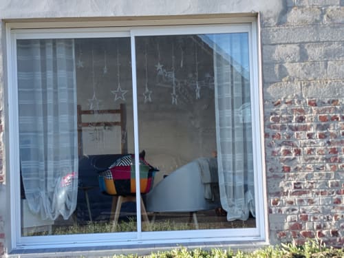 Vue du séjour de l'appartement Les Escardines avec mobilier, fauteuil et décoration d'étoiles suspendues visibles à travers les portes vitrées