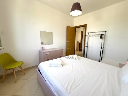 Camera luminosa alla Puglia Estate con letto queen, poltrona gialla, cassettone e comfort moderni a Nardò, Italia