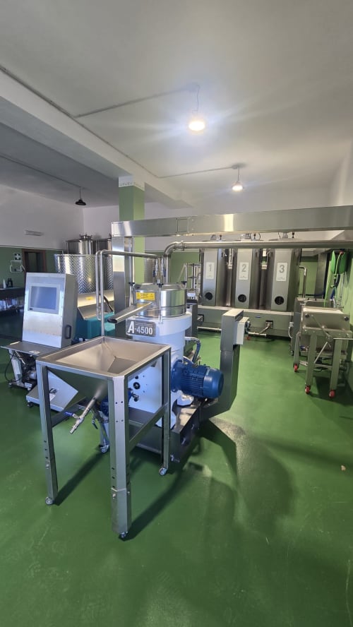 Industrial wine production facility at Fogliantica agriturismo with stainless steel equipment and green epoxy flooring