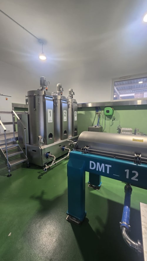 Industrial dairy equipment with three stainless steel tanks labeled 1, 2, 3 in a green-floored facility