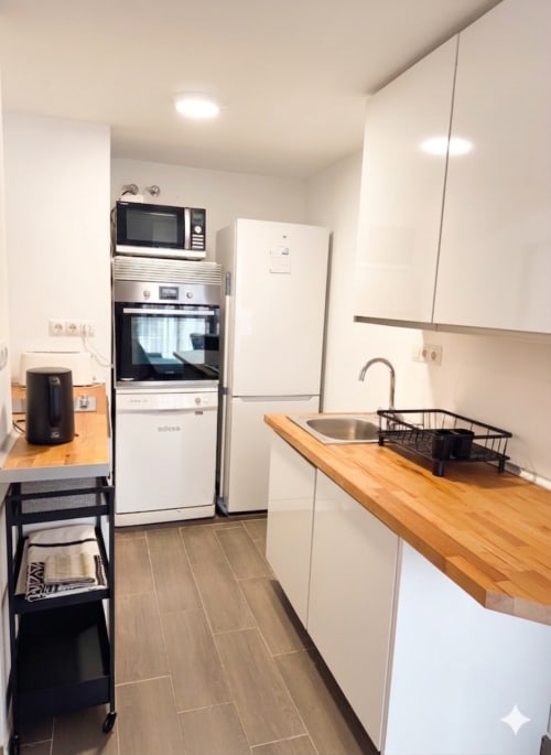 Kitchenette moderna del apartamento Torre Sol Y Playa en Torremolinos con encimera de madera, fregadero y electrodomésticos blancos