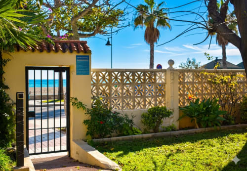 Apartamento amarillo con puerta negra y valla decorativa, vistas al mar en Torremolinos, España