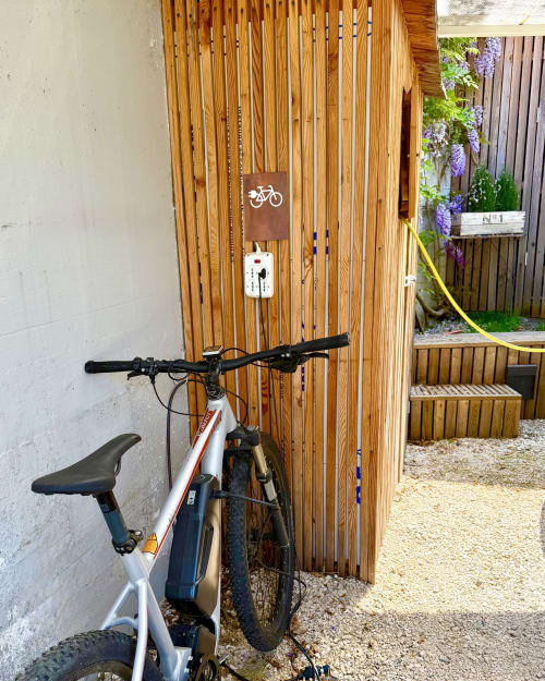 Bicicletta elettrica parcheggiata alla stazione di ricarica del Verdolivo B&B a Sale Marasino con parete in listelli di legno e giardino