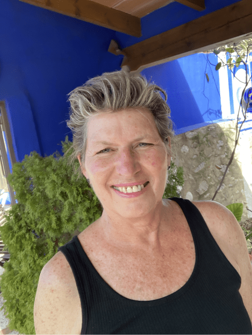 Mujer sonriente en la terraza azul del hotel boutique Casa Gallinera en Alicante, España, rodeada de plantas