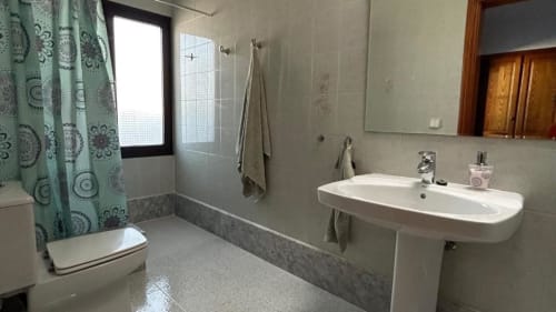 Modern bathroom in Villa Estrella Polar with white sink, shower with teal curtain, and tiled flooring in Tahiche