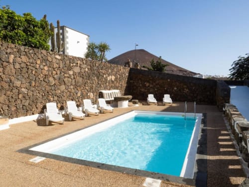 Crystalline swimming pool with white loungers and volcanic mountain views at Villa Estrella Polar, Tahiche