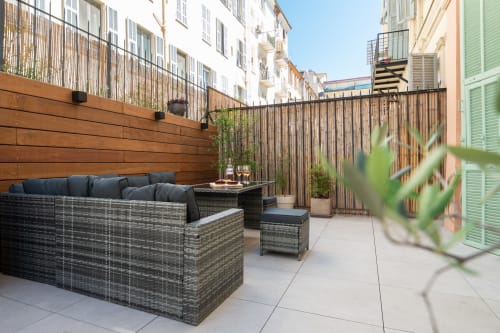 Modern terrace at Enjoy Nice hotel in Nice, France with wicker seating, dark cushions, wooden privacy screen and city views