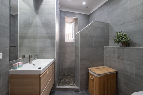 Modern bathroom in Zen apartment at Enjoy Nice hotel with gray tile, wooden vanity, walk-in shower, and potted plant