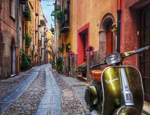 Vintage Vespa su pittoresca strada di ciottoli a Bosa, Italia con edifici storici colorati