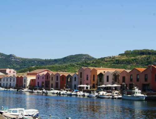 Case colorate sul lungomare di Bosa con barche ormeggiate e lo sfondo collinare