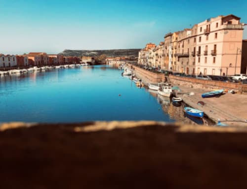 Colorati edifici sul lungomare e barche da pesca a Bosa, Italia, sede di Regnos Altos Boutique Rooms