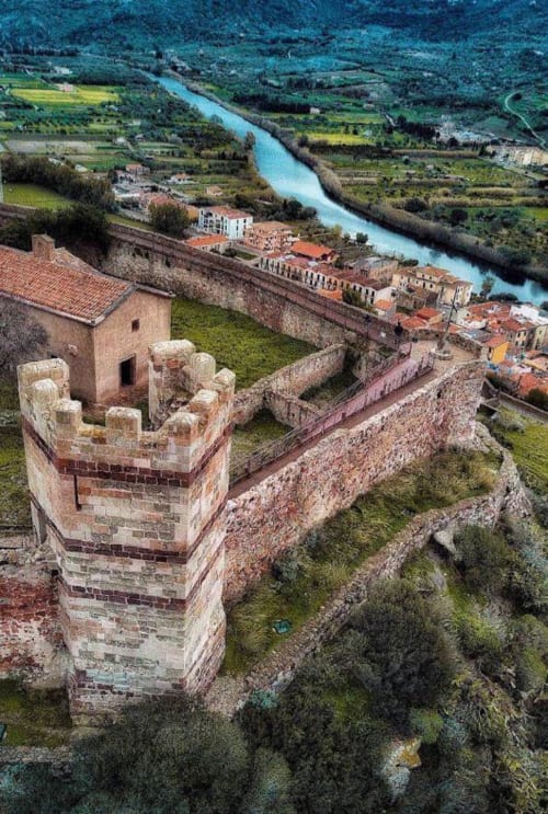 Ruderi di fortezza medievale dominano il fiume turchese e il villaggio di Bosa immerso nella verdeggiante valle italiana