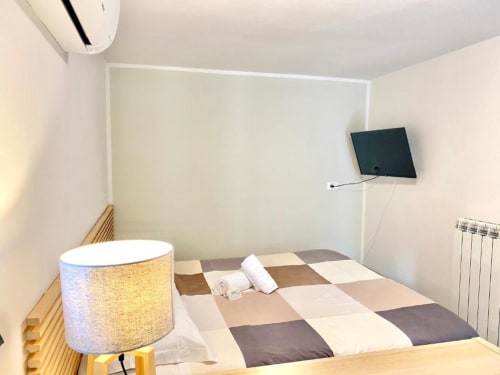 Cozy single room at The Green Gate Pisa with patchwork bed, wall-mounted TV, desk lamp, and heating radiator